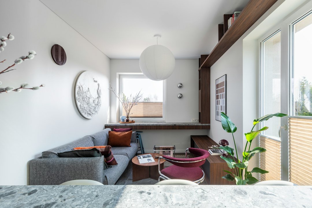 Modern living room with grey sofa, red armchair, and window